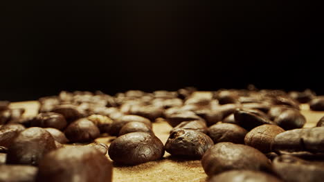 Close-camera-movement-through-fresh-coffee-beans-laying-on-a-wooden-surface