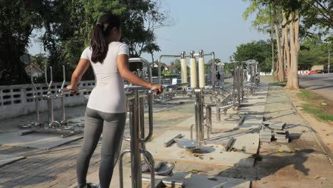 A-woman-working-in-an-outdoor-gym-exercising-and-toning-her-hips-and-thighs---Wide-shot-from-behind-the-girl