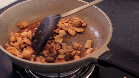 Cooking-delicious-pork-with-sugar-and-mixing-the-flavors-with-a-black-ladle---Close-up