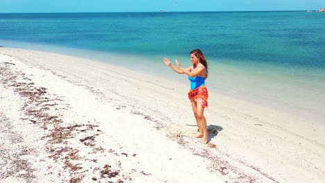 Sportlerin,-Junge-Frau,-Die-Yoga-Macht-Und-Auf-Einem-Fuß-Steht-Und-über-Dem-Weißen-Sand-Eines-Exotischen-Strandes-Mit-Blauem-Meereshintergrund-Balanciert