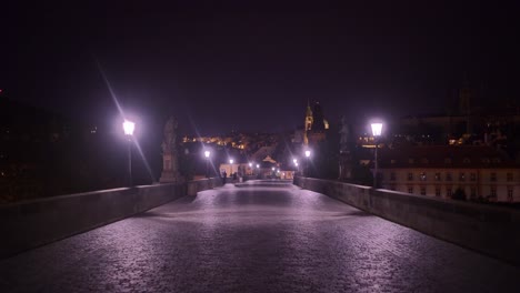 POV-Spaziergang-Entlang-Der-Karlsbrücke-In-Prag-Bei-Nacht,-Beleuchtet-Von-Laternenpfählen