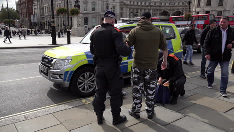 Police-officers-wearing-protective-face-masks-detain-and-search-a-man-for-weapons-after-he-attended-a-Coronavirus-conspiracy-protest-at-Trafalgar-Square-carrying-a-riot-shield
