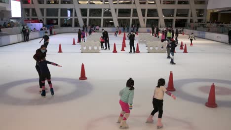 Menschen-Jeden-Alters-Werden-Dabei-Beobachtet,-Wie-Sie-In-Einem-Einkaufszentrum-In-Hongkong-Indoor-Eislaufen-Lernen