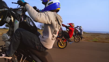 Extremsportler-Fahren,-Während-Drei-Männer-Auf-Den-Nebenstraßen-Indonesiens-Motorrad-Wheeies-Ausführen