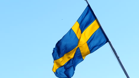 Bandera-Sueca-Ondeando-En-El-Viento,-Fondo-De-Cielo-Azul