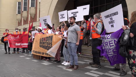 Protestors-on-the-London-Renters-Union-housing-demonstration-opposing-eviction-during-the-Coronavirus-pandemic,-stand-hold-placards-and-banners-in-front-of-Stratford-Magistrates-Court