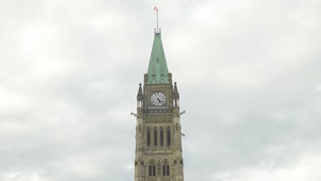 Torre-Del-Reloj-En-El-Edificio-Parliament-Hill-En-Ottawa,-Ontario,-Canadá,-Con-Bandera-Canadiense-Ondeando-En-Verano