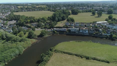 Drone-shot-approaching-a-bend-in-the-Exe-River-on-a-sunny-afternoon-in-Devon,-UK