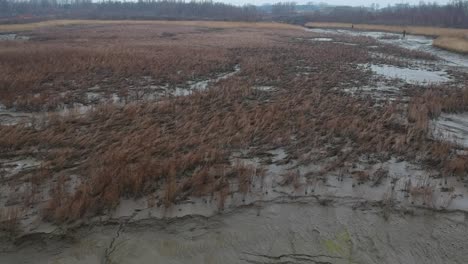 Aerial-forward-over-mud-dry-river-bed-field-muddy-landscape-cloudy-day