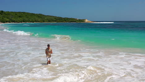 Guy-standing-in-the-sea-flying-a-drone,Half-Moon-bay-beach,Antigua,Caribbean