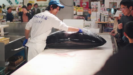 Mann-Legt-Den-Roten-Thunfisch-Auf-Einen-Weißen-Tisch,-Bereit-Zum-Sezieren-Mit-Dem-Publikum-Auf-Dem-Toretore-Ichiba-Fischmarkt,-Wakayama,-Japan
