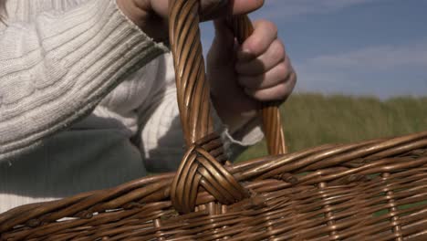 Woman-holding-woven-basket-in-field-close-up-shot