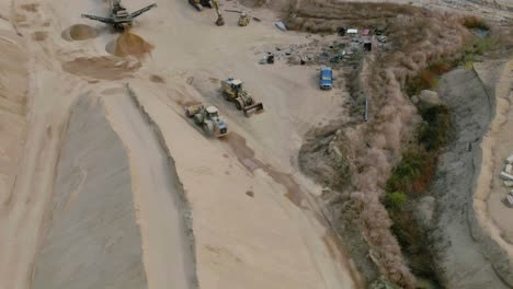 Aerial-moving-view-of-Bulldozer-working-in-rock-quarry-driving-around-the-site
