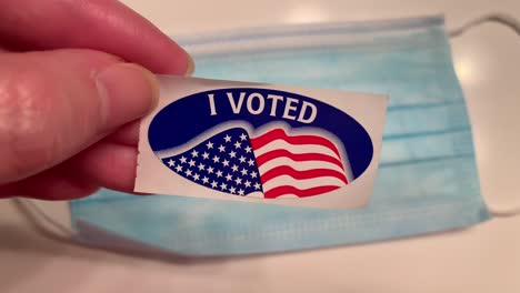 "I-VOTED"-sticker-over-a-blue-surgical-mask