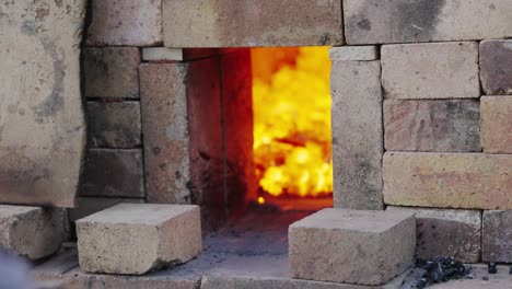 Person-stacking-bricks-in-front-of-the-opening-on-their-kiln-to-control-air-flow-and-heat---Pottery-and-furnace-concepts