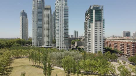 Flying-Above-Lush-Trees-Towards-Contemporary-Office-Buildings-In-Puerto-Madero,-Buenos-Aires,-Argentina---low-aerial