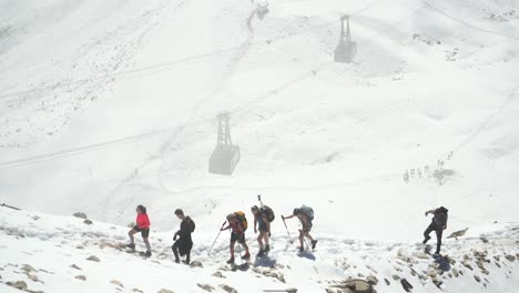 Kletterer-Auf-Schneeweg-In-Den-Bergen-Oberhalb-Der-Seilbahnen-Im-Hintergrund