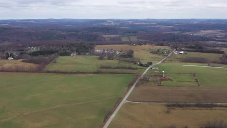 Aerial-view-above-the-rural-road-in-the-countryside,-view-of-the-campground-by-the-Pine-Cradle-Lake-in-Rome-Bradford-County-Pennsylvania,-Agricultural-Field,-Panoramic-Landscape