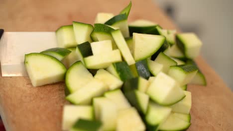 Der-Koch-Gießt-Gehackte-Zucchini-Mit-Einem-Messer-Vom-Holzschneidebrett,-Bereitet-Den-Gemüsesalat-Zu,-Kocht-Mit-Gemüse,-Vitaminen-Und-Gesunder-Ernährung,-Vegetarische-Gerichte