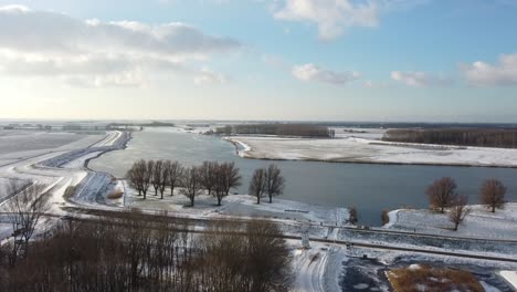 Flying-towards-a-river-with-a-drone-above-a-frozen-ditch-in-a-winter-landscape