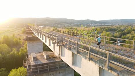 Girl-jogging-on-bridge-at-sunset-in-4k,-pan-shot