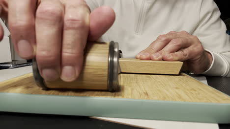 Male-hand-Sharpening-Knife-with-modern-grindstone-on-wooden-board