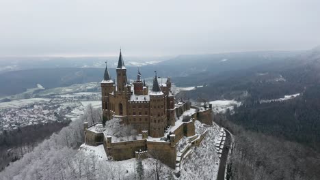Aerial-view-rotating-around-medieval-Castle-Hohenzollern-on-a-snowy-day-during-winter-in-Swabia,-Germany