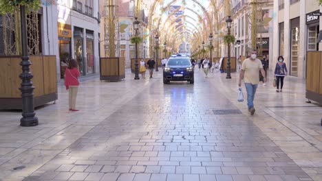 Police-Car-Driving-Towards-The-Camera---Calle-Larios-In-Malaga,-Spain---wide-shot