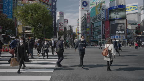 Asian-People-Crossing-At-Shibuya-Scramble-Crossing-With-Shopping-Malls-In-Background-During-Pandemic-In-Tokyo,-Japan
