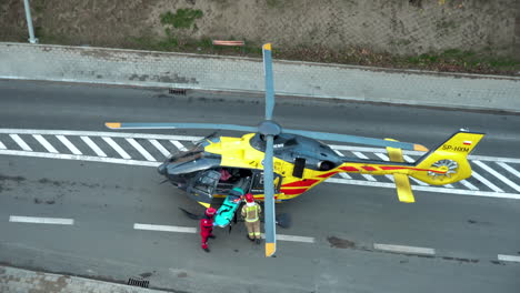 polish-helicopter-rescue,-air-ambulance-service-landing-on-the-center-of-road-in-city,-the-rescue-crew-prepares-the-stretcher