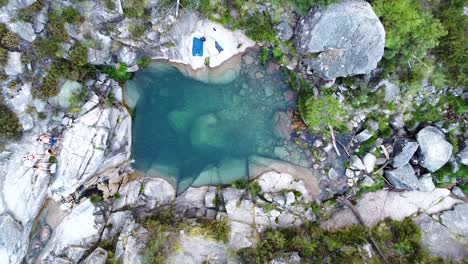 Small-blue-lagoon-created-from-waterfall-in-Peneda-Geres-National-Park,-Portugal,-Europe---drone-going-up