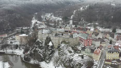 Aerial-view-of-medieval-Loket-castle,-Czech-Republic-in-snowy-winter-landscape