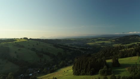 Wunderschöne-Landschaft-Mit-Wiesen,-Die-Im-Frühling-Durch-Bewaldete-Hügel-Rollen---Drohnenaufnahme-Aus-Der-Luft