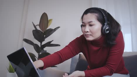 Freelance-woman-redshirt-using-tablet-with-headphone-for-meeting-online-at-home
