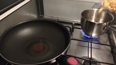 Pasta-being-poured-into-pot-filled-with-water-standing-on-stove-top