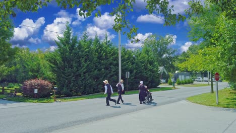 Una-Familia-Amish-Con-Uno-En-Silla-De-Ruedas-Caminando-A-Casa-Después-De-La-Iglesia-En-Un-Hermoso-Día-De-Verano
