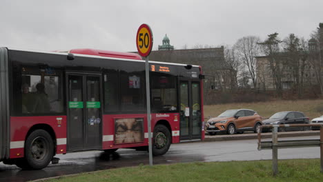 Red-articulated-bus-in-Stockholm-driving-and-turning-onto-road,-slow-motion