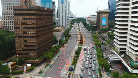 Cinematic-aerial-forward-over-city-center-busy-street-and-car-traffic,-MH-Thamrin