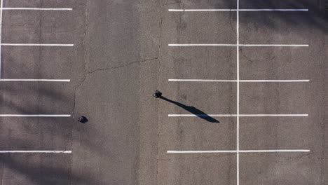 A-top-down-shot-directly-over-an-empty-parking-lot-with-a-man-playing-with-an-electric-remote-controlled-car