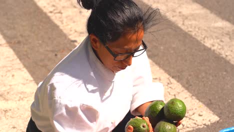 Latin-woman-choosing-avocados-in-market