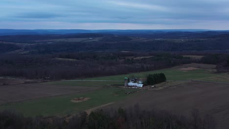 Moody,-aerial-shot-of-a-farm-in-rural-Rome-Pennsylvania-with-animals-grazing-on-a-cloudy-day