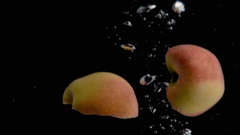 Apple-Falling-into-Water-Super-Slowmotion,-Black-Background,-lots-of-Air-Bubbles,-4k240fps