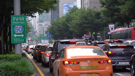Primer-Plano-Del-Tráfico-De-Automóviles-Pasando-El-Cartel-De-Gangnam-Daero-Cerca-De-La-Estación-De-Metro-De-Gangnam-En-Seúl-Corea-Del-Sur-Durante-El-Verano