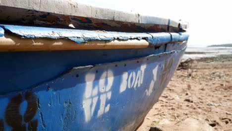 Spray-painted-love-boat-graffiti-abandoned-beached-wooden-ship-on-sandy-coastline-waterfront-dolly-left
