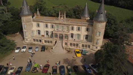 Aerial-drone-view-of-an-exhibition-of-old-vintage-cars-in-front-of-a-castle
