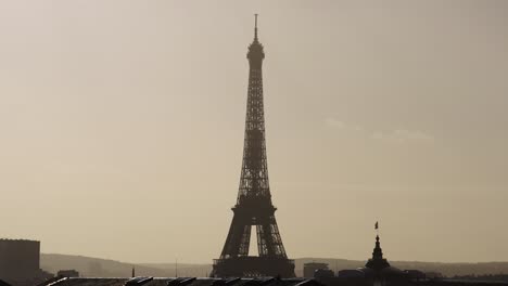 Dunstiger-Blick-Auf-Den-Eiffelturm-Während-Der-Goldenen-Stunde-Mit-Dächern-Und-Vögeln-In-Zeitlupe-4k-60p