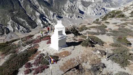 Turistas-De-Pie-Cerca-De-Dos-Pequeñas-Estupas-Con-Banderas-De-Oración-En-La-Cima-De-Una-Montaña-En-El-Circuito-De-Annapurna-Trek,-Nepal