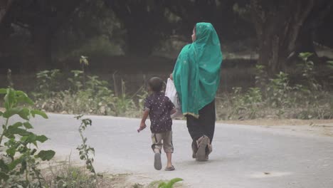 Woman-along-her-kid-walking-along-a-village-road