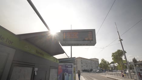 Straßenbahnhaltestelle-Mit-Passanten-Und-Plakat-Mit-Ankunftszeiten,-Blick-Nach-Oben,-Schwenk-Nach-Links