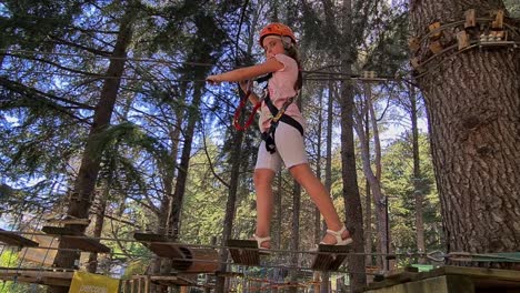 Adventurous-girl-child-cross-suspended-bridge-at-kids-rope-adventure-park